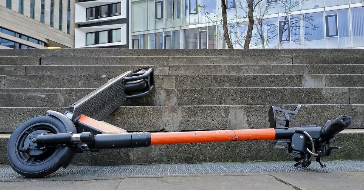 Electric scooter laying on stairs on footpath